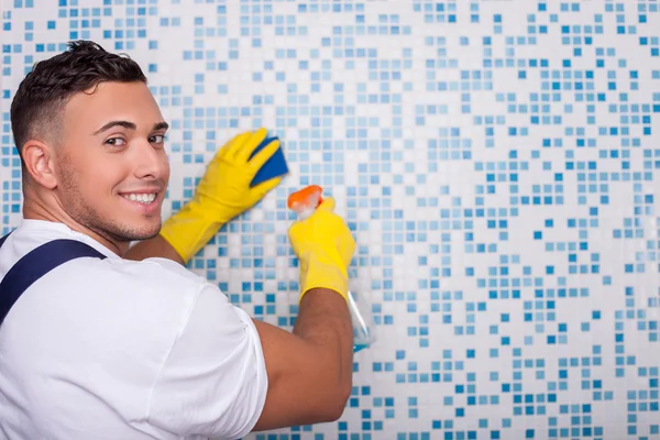 Atractivo limpiador joven está lavando la pared con un wisp — Foto de Stock