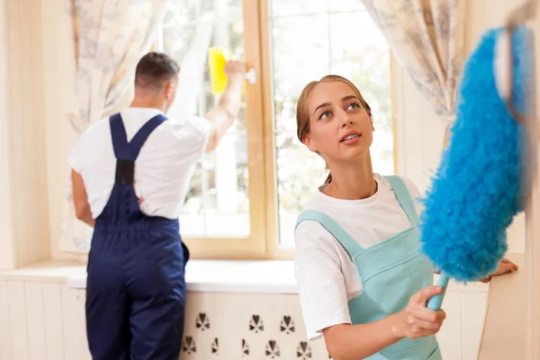 Hermosa joven criada y su colega están limpiando una habitación — Foto de Stock