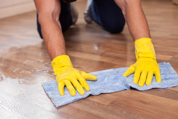 Limpiador joven calificado está fregando el piso en una casa —  Fotos de Stock