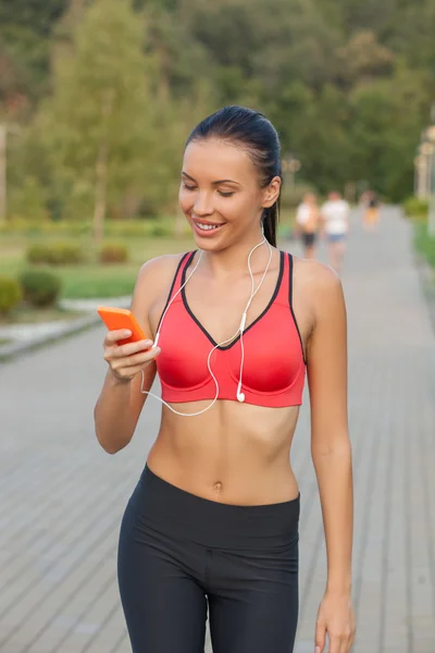 Beautiful healthy female runner is using telephone — Stok fotoğraf