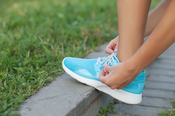 Mujer joven está arreglando cordones de sus zapatillas — Foto de Stock