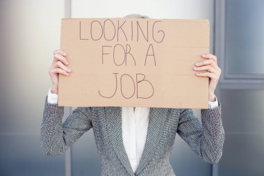 Cheerful young businesswoman is showing a billboard with inscription