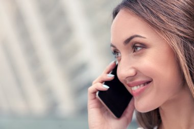 Cheerful young woman is using phone for communication