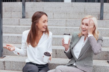 Beautiful young female colleagues are communicating with joy