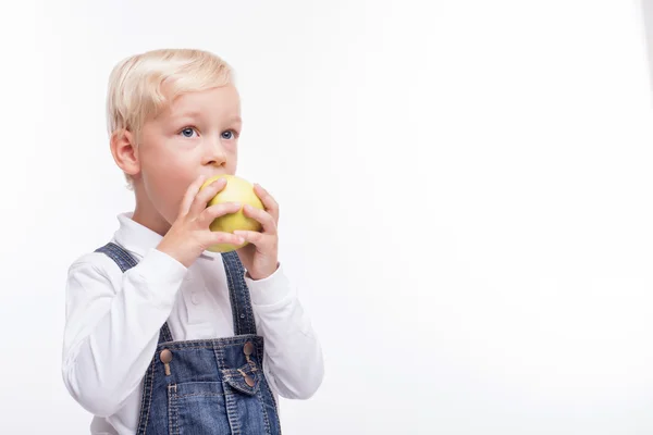 Bonita criança masculina está comendo frutas verdes — Fotografia de Stock