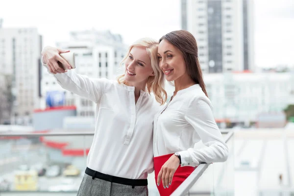 Cheerful young businesswomen are photographing themselves on telephone