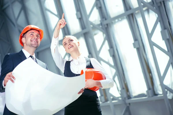 Hermosos jóvenes ingenieros están discutiendo la construcción de edificios — Foto de Stock