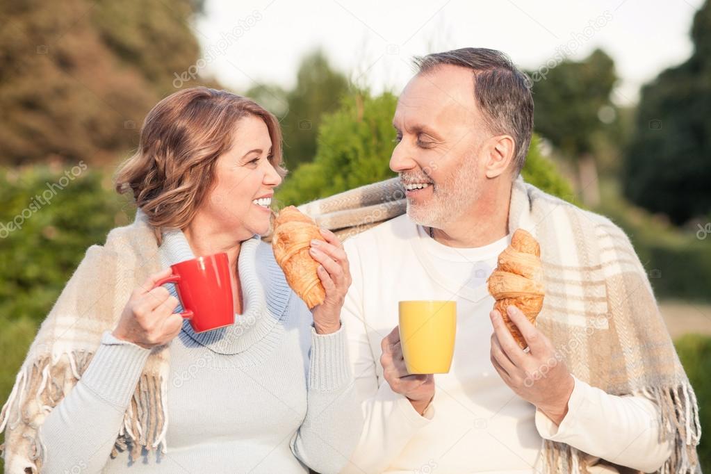 Cute old loving couple is making picnic outdoors