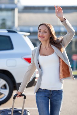 Cheerful young woman is meeting with someone at the airport