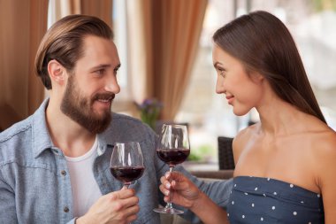Cheerful loving couple is enjoying red drink in restaurant