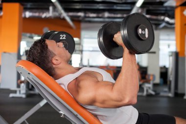 Attractive young male sportsman is training in gym