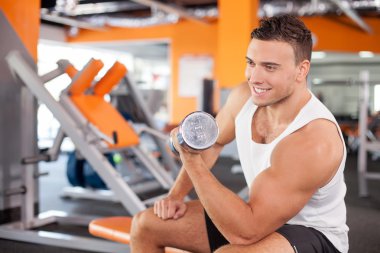 Handsome fit male athlete is raising weight in gym