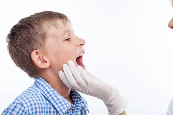 Pretty young female pediatrician is examining throat of kid — Stok fotoğraf