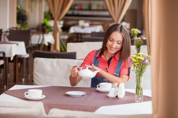 Beautiful hipster girl is enjoying hot drink in cafe — Zdjęcie stockowe