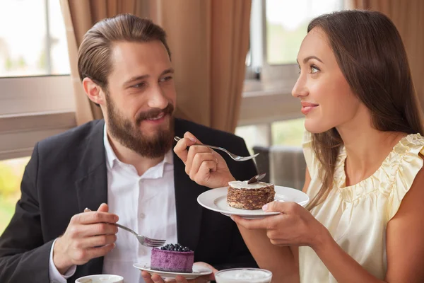 Attractive man and woman are tasting sweet food in cafe — Stock Photo, Image