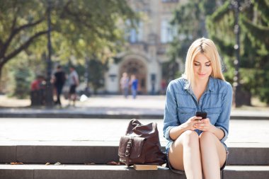 Beautiful young woman is using telephone after studying