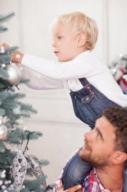 Cheerful family is preparing Christmas tree for celebration