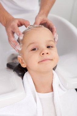 Professional young barber is making hairwash for client