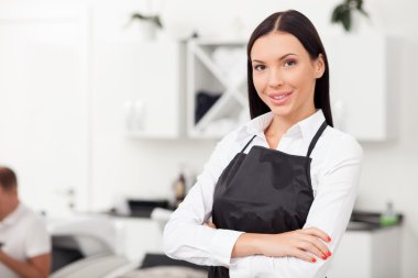 Beautiful young female hairstylist is working in salon