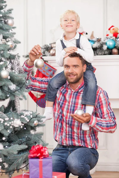 Homem bonito ajuda a criança a decorar a árvore de Ano Novo — Fotografia de Stock