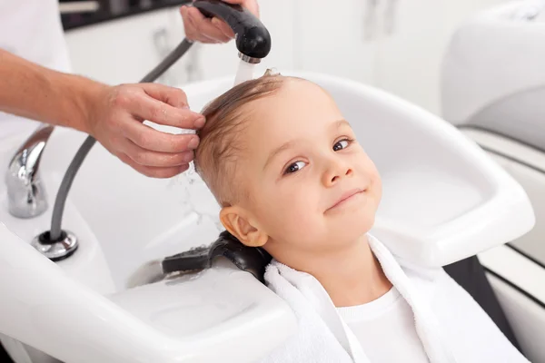 Cheerful male child is having hair washed in salon — Stock fotografie
