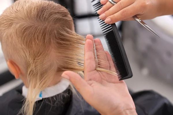 Habilidade jovem cabeleireiro feminino está fazendo corte de cabelo para criança — Fotografia de Stock
