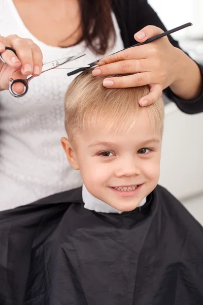 garçon de 10 ans dans un coiffeur après une coupe de cheveux à la mode  devant un miroir.Un petit enfant dans un salon de beauté regarde la caméra  poser Photo Stock 