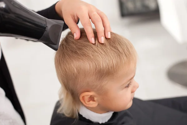 Barbeiro fêmea experiente está fazendo penteado para criança — Fotografia de Stock