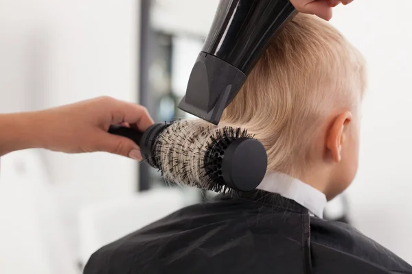 Alegre joven peluquero hembra está secando el cabello humano —  Fotos de Stock