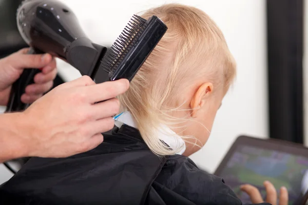 Cabeleireiro jovem experiente está definindo o cabelo da criança — Fotografia de Stock