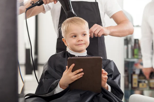 Cheerful young hairdresser is working with hair-drier — Stockfoto