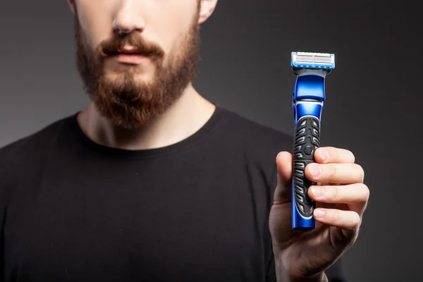 Cheerful young man with beard is carrying shaver — Stockfoto