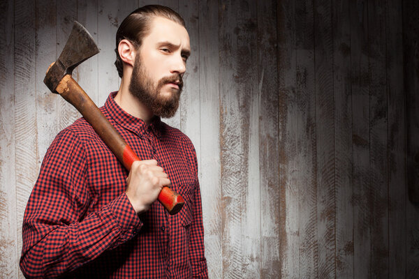 Красивый молодой парень с бородой и топором
