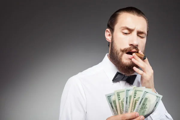 Cheerful young bearded businessman is carrying money