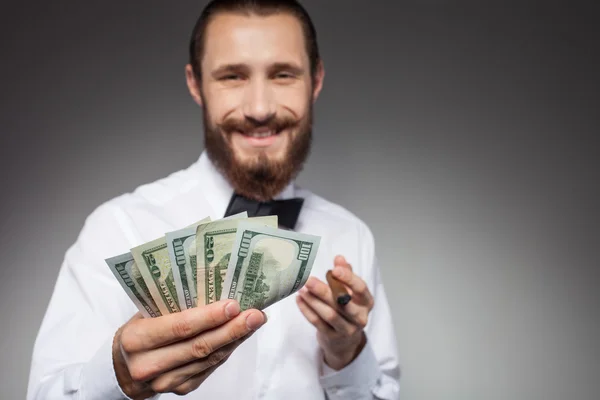 Attractive young man with dollars is smoking — Stockfoto