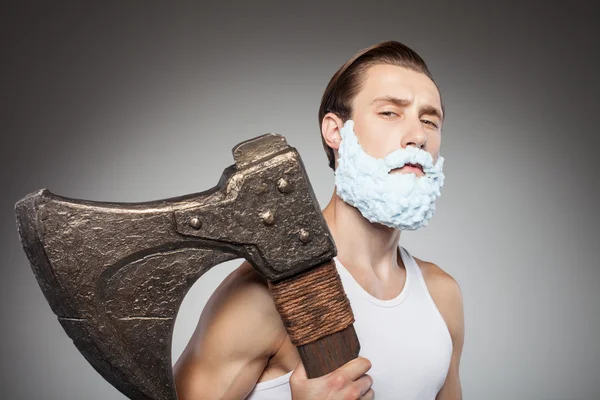 Cheerful young man is carrying axe during shaving — Stock fotografie