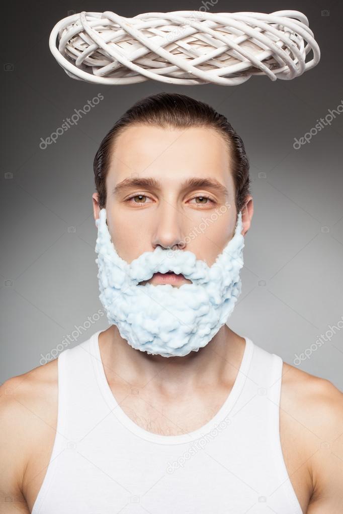 Cheerful bearded man is making fun during shaving