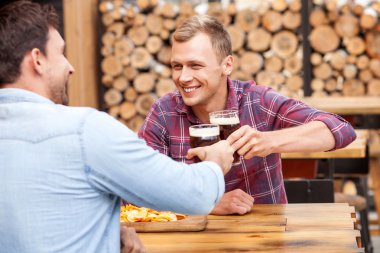 Handsome young guys are swigging lager in bar clipart