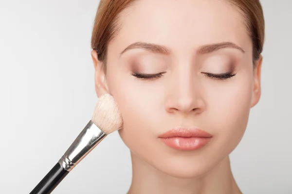 Professional makeup artist is treating attractive girl — Zdjęcie stockowe