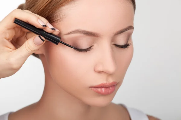 Skilled young beautician is doing make-up for girl — Stockfoto