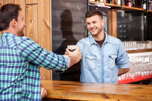 Handsome bartender is serving his customer in bar — Stockfoto