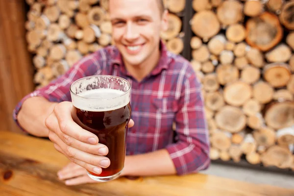 Cheerful man is swigging lager in pub — Stockfoto