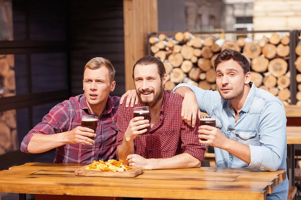 Glada unga män tittar på spelet i pub — Stockfoto