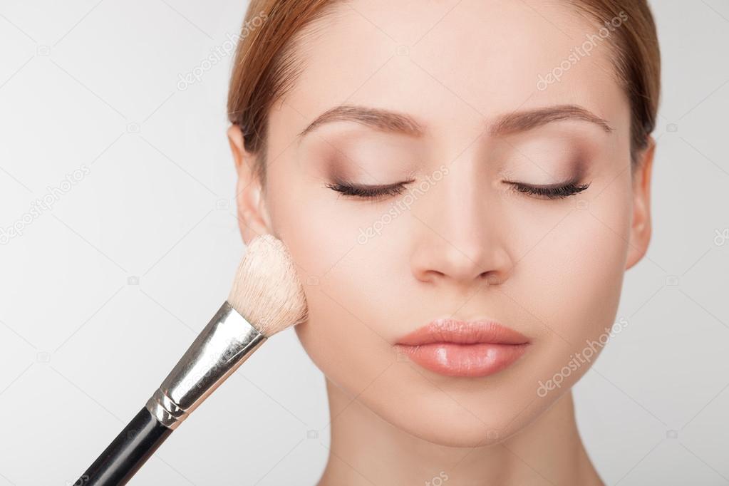 Professional makeup artist is treating attractive girl