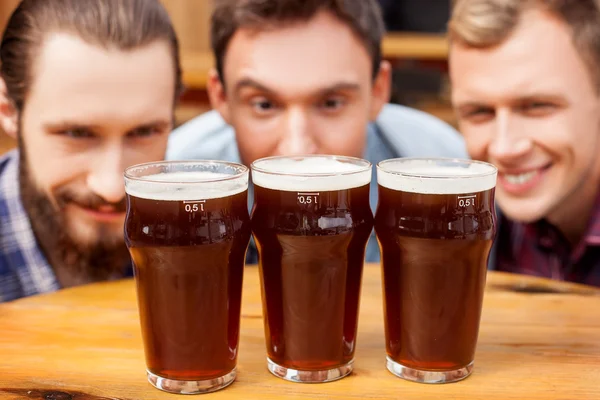 Amigos do sexo masculino atraentes estão assistindo em bebidas no bar — Fotografia de Stock