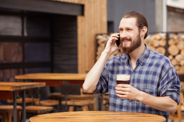 Stilig skäggig kille kommunicerar på telefon i pub — Stockfoto