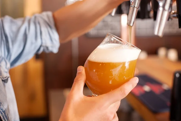 Веселый молодой бармен наливает пиво в паб — стоковое фото
