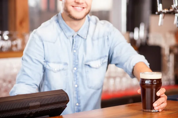 Vrolijke jonge mannelijke barman ten dienste staat van klant in pub — Stockfoto