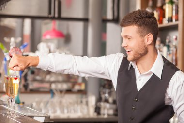 Handsome male barman is creating alcohol drinks