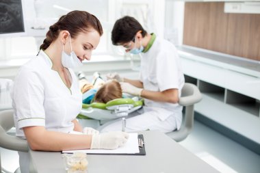 Cheerful young dentist is examining human oral cavity clipart